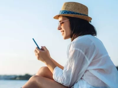 reading phone on beach while reading Real Investing for Beginners