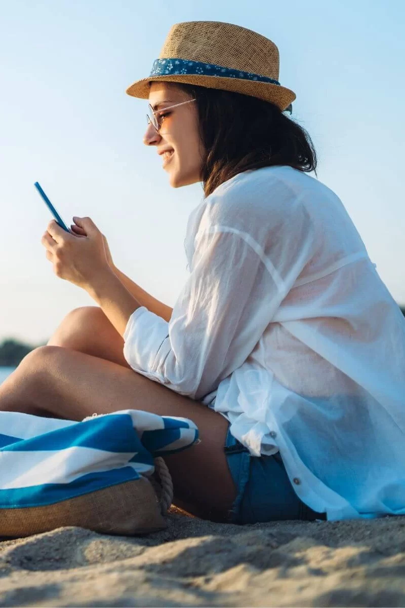 reading phone on beach while reading Real Investing for Beginners for tablet