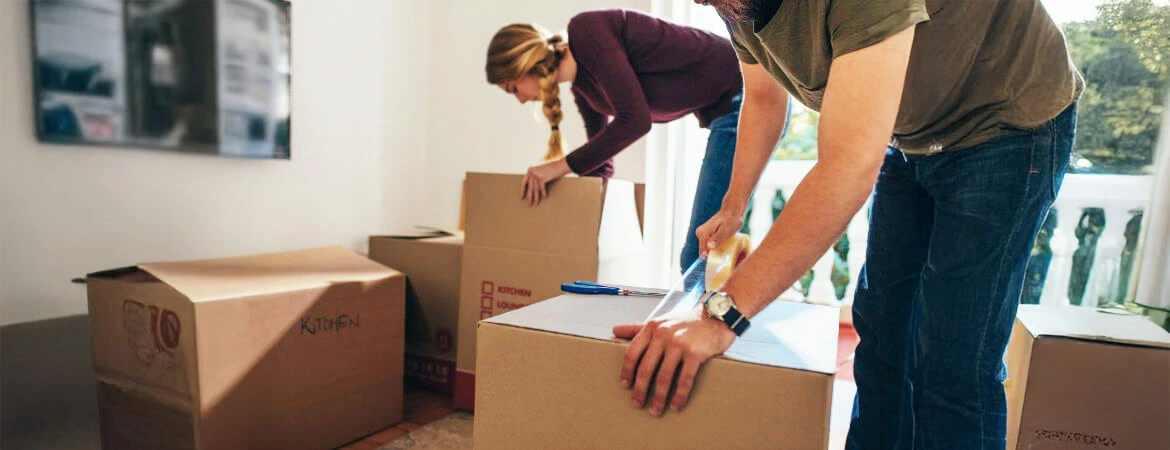 A couple carefully packing boxes, symbolizing the organization of probate estate belongings after death. This image reflects the process of managing items during probate. Reach out to Kid Breukelen Realty Group for expert help with estate management.